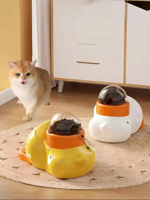 Two small animal feeders shaped like ducks on a wooden floor with a cat in the background
